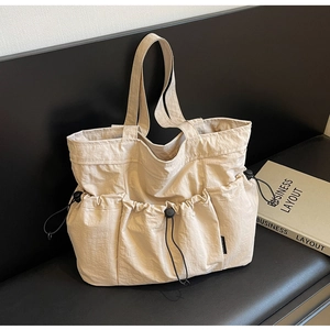 Detailed view of the off-white pleated tote bag showing multiple utility pockets and texture