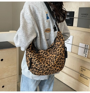 Detail of leopard print canvas crossbody bag on model with adjustable strap and zip