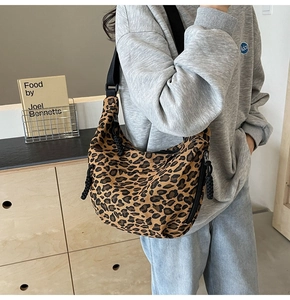 Detail view of leopard print canvas dumpling bag with adjustable wide strap and side zipper