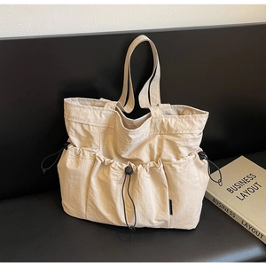 Close-up of beige ruched tote bag with drawstring utility pockets and nylon texture