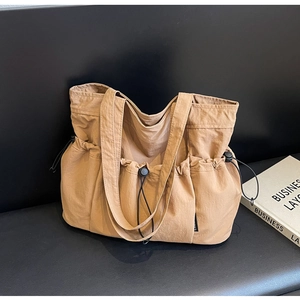 Detail view of khaki pleated tote bag with adjustable drawstring pockets and canvas handles