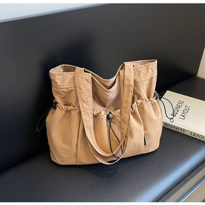 Detail of khaki tote bag with drawstring side pockets on dark leather background