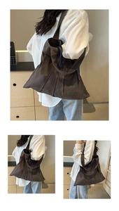 Detail of dark brown canvas tote bag featuring unique vertical pleated texture and long strap