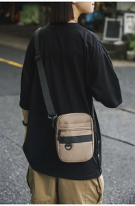 Outdoor shot of a techwear khaki crossbody bag with nylon fabric and D-ring hook detail