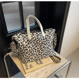 Detail view of canvas leopard print tote bag featuring leather handles and buckle side pocket