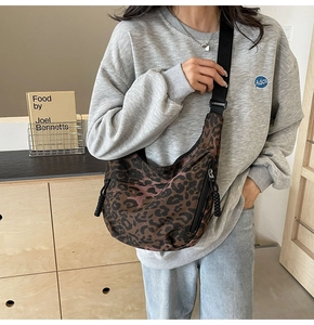Detail of leopard print canvas crescent bag showing wide nylon strap and half-moon design
