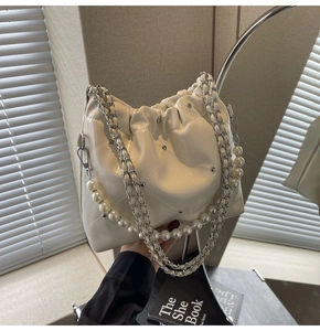 Close-up of cream cloud bag featuring quilted texture, pearl chain and silver studs