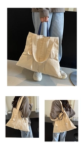 Detailed view of cream canvas tote bag showing side gussets and navy contrast handles