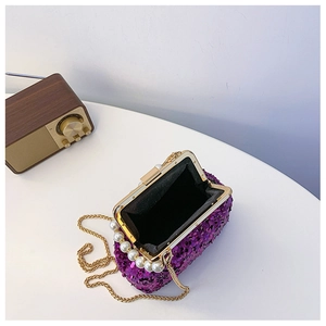 Detail der lila Pailletten-Muscheltasche mit Goldkette und elegantem Perlengriff