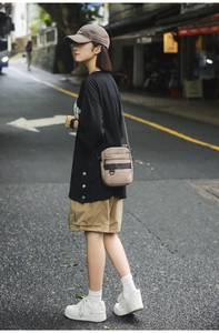 Street view of a beige crossbody bag showing its compact multi-pocket design on model