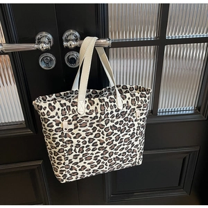 Detail of leopard print canvas tote bag hanging on door with functional front pocket