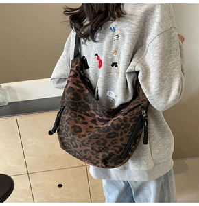 Detail view of leopard print crescent bag with adjustable wide strap and zip pocket