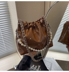 Close-up of brown quilted bucket bag with pearl chain and shiny silver studs detail
