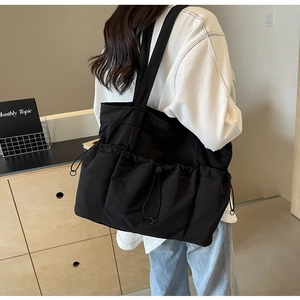 Detail shot of black tote bag with three drawstring outer pockets for commute and school