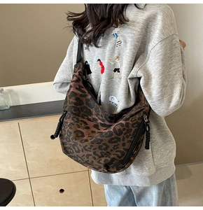 Close-up of leopard print canvas bag with wide black strap and hobo moon shape