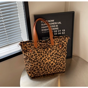 Detail of leopard print canvas tote bag with brown leather handles and metal rivets
