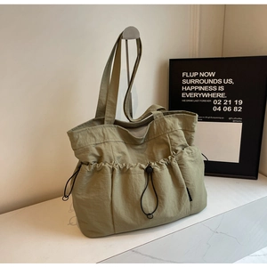 Detail of khaki pleated nylon tote bag showing drawstring pocket and textured material