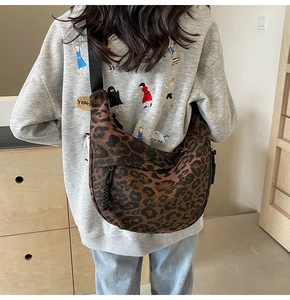 Close-up of leopard print canvas crescent bag with black wide strap and zipper detail