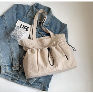 Detail of beige pleated nylon tote bag featuring three functional drawstring pockets