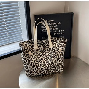 Detailed macro view of leopard print canvas tote bag with outer pocket and zipper on table