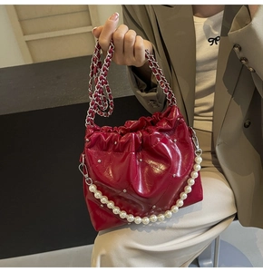 Detail of red quilted leather bucket bag with silver studs and pearl handle