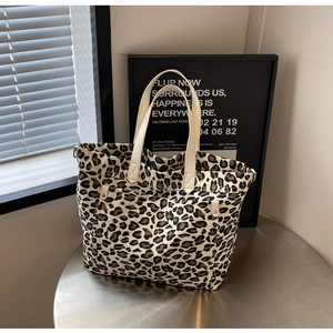 Detailed shot of leopard print canvas tote bag with reinforced faux leather handles on table