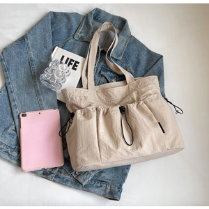 Detailed view of beige pleated tote bag with three drawstring pockets and wide strap