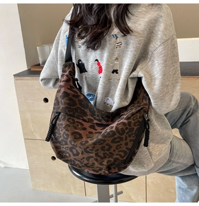 Detailed side view of leopard print canvas crescent bag with black adjustable strap