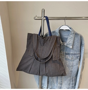 Close-up of canvas tote bag showing orange topstitching and denim handles