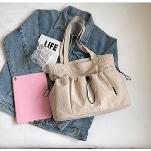 Detail of cream nylon tote bag with drawstring pockets on casual denim background
