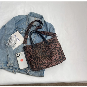 Close-up of leopard print canvas tote bag with adjustable shoulder strap on denim