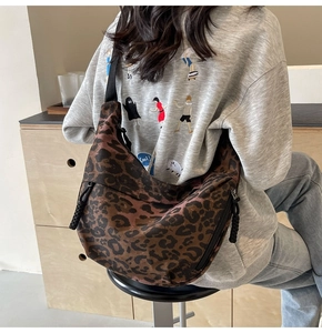 Detailed view of leopard print canvas dumpling bag with black zipper and wide strap