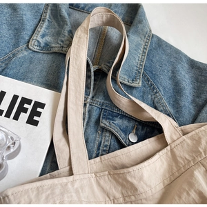 Detail of light beige tote bag handle with neat stitching on soft wrinkled fabric surface