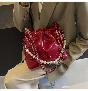 Deep red quilted bucket bag featuring a large pearl chain and silver metal accents