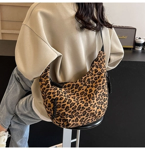 Detailed back view of a large leopard print canvas hobo bag worn by a model in a cozy room