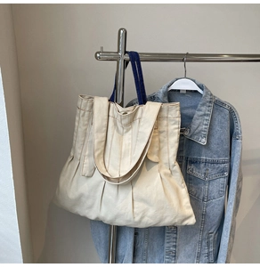 Detail of canvas tote bag showing soft pleats and contrasting dark blue handles