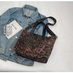 Detail of leopard print canvas tote bag with black handles and adjustable crossbody strap