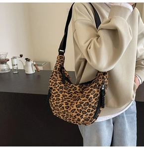 Detailed leopard print canvas dumpling bag with adjustable black strap and zipper detail
