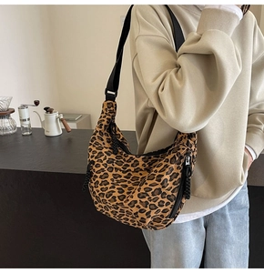 Detail of leopard print canvas crescent bag featuring adjustable black nylon shoulder strap