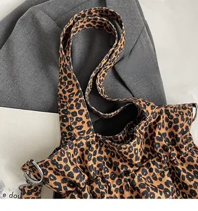 Detail of leopard print canvas tote bag featuring silver metal rings and long shoulder straps