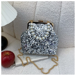 Silberne Pailletten-Abendtasche mit weißem Perlengriff und goldener Kette auf Textur