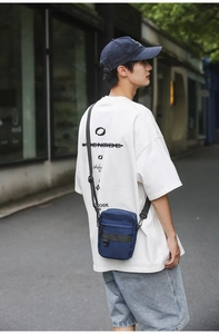 Close-up of a navy blue nylon crossbody bag featuring durable zippers and a shoulder strap