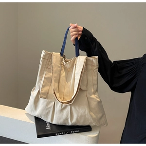 Detail view of large canvas tote bag with contrast stitching and navy blue webbing handles
