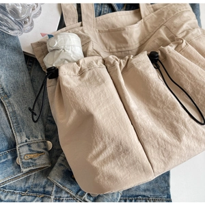Detail shot of khaki tote bag with drawstring pockets holding an umbrella