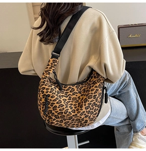 Detail of leopard print canvas crossbody bag with adjustable wide strap and crescent shape