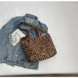 Detail of leopard print canvas tote bag with brown handles and wide adjustable shoulder strap