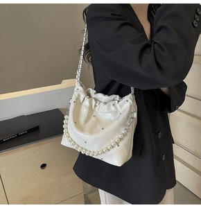 Detail of white quilted handbag featuring silver chain and large faux pearl decorative strap