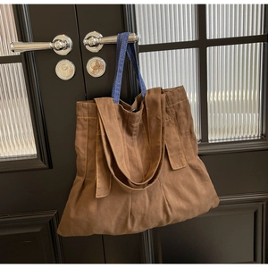 Close-up of vintage canvas tote bag with contrast denim straps hanging on a door handle