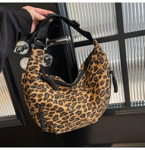 Detail of leopard print canvas crescent bag with adjustable black strap on door handle