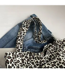 Dettaglio dei larghi manici in tela leopardata su una capiente borsa shopper da donna